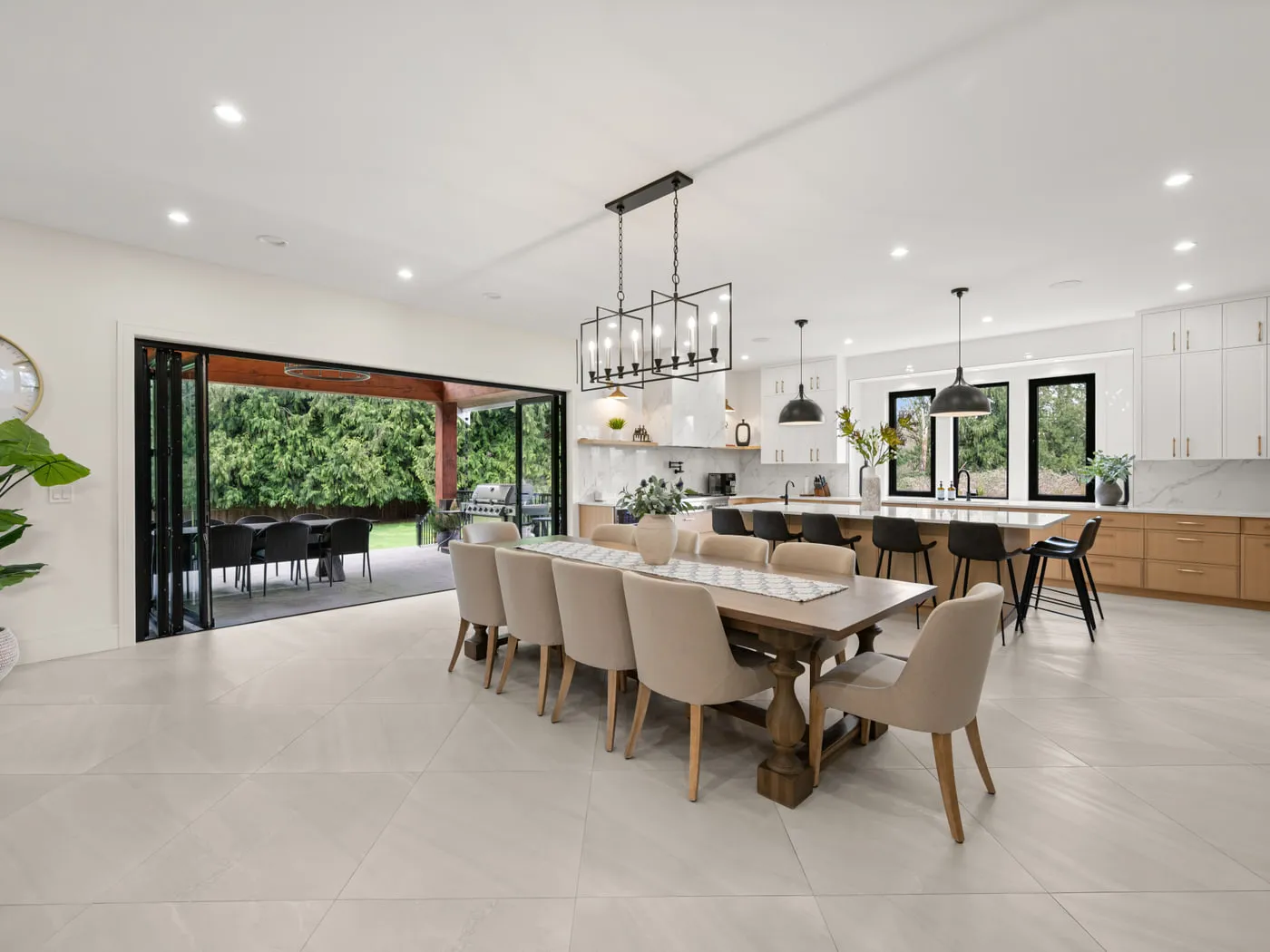A finished open-plan dining area with a long table, pendant lighting and full-height glazing onto the garden.