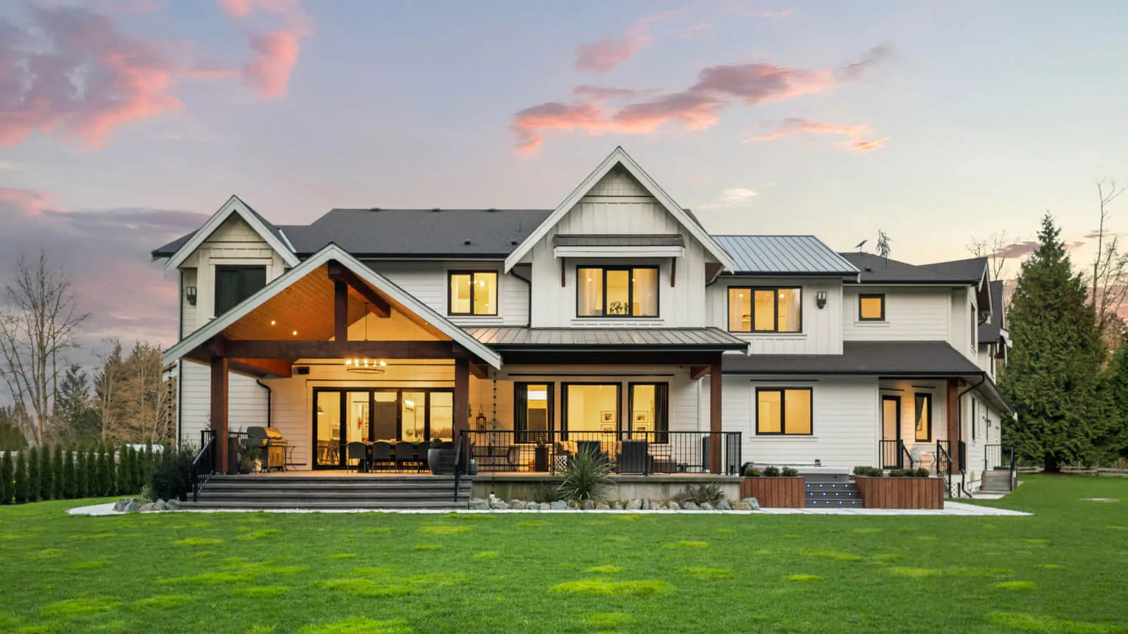 The rear of a finished home with a covered deck and a level lawn.